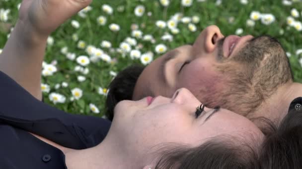 Sladký a romantický pár ležící na trávě chatování — Stock video