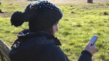 sevimli kadın parkta Smartphone iletileri okur