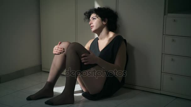 Szomorú fiatal nő sírva ül a földön félhomályban — Stock videók