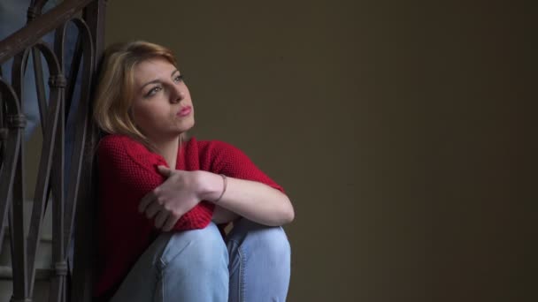 Traurige blonde Frau, die auf der Treppe sitzt, wird vom Freund erreicht, der sie tröstet — Stockvideo