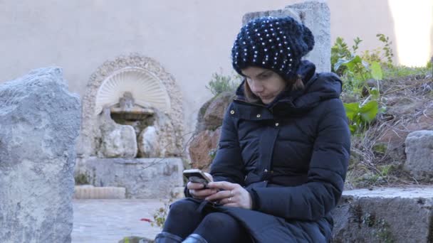 Donna seduta da sola in un giardino chat con smartphone — Video Stock