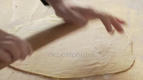Жіночі руки прокатують шпильку на свіже тісто, щоб зробити піцу — стокове відео