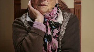 eski büyükanne oturan kameraya bakarak ve gözlerini kapatır