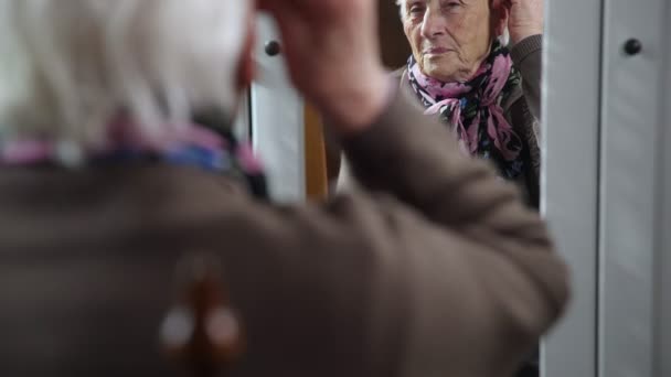 Грустная и депрессивная старуха в зеркале касается волос — стоковое видео