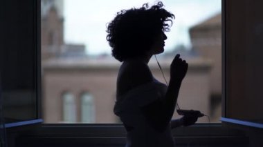 seksi kadın arkadan aydınlatmalı pencere dans etmek ve şarkı söyler silüeti