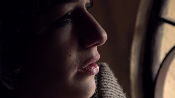 Profil de chère et triste femme regardant par la fenêtre dans l'obscurité 