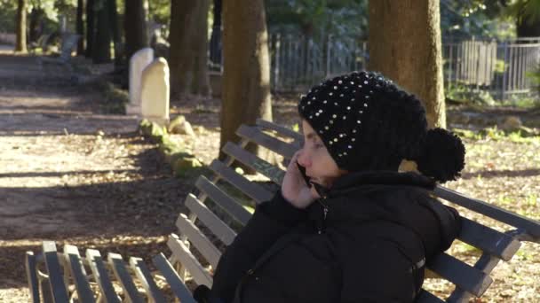 Profil de la femme au parc assis sur un banc tout en parlant au téléphone — Video