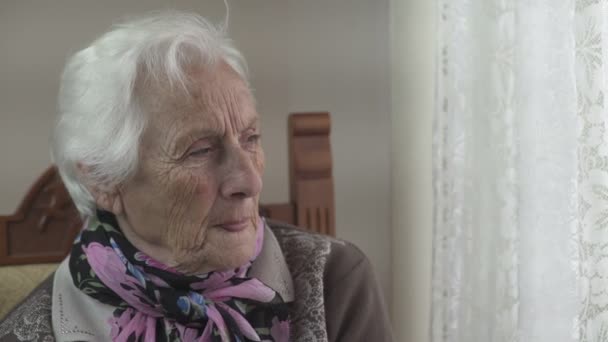 Очень старая депрессивная женщина, сидящая, выглядывающая в окно — стоковое видео