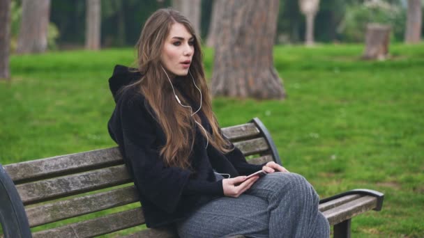 Wütende schöne Frau, die auf der Bank sitzt und mit dem Smartphone spricht — Stockvideo