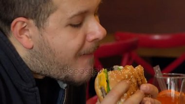 Aç adam bayt büyük bir burger. Adam yeme burger yakın çekim