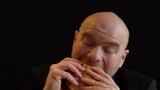 Głodny łysy mężczyzna jedzenie burger z bliska — Wideo stockowe