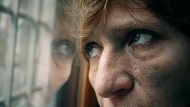 Faltige Augen trauriger, depressiver, reifer Frau, die aus dem Fenster schaut — Stockvideo