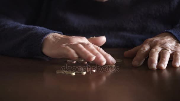Gepensioneerde oude vrouw hand tellen munten op tafel, close-up — Stockvideo