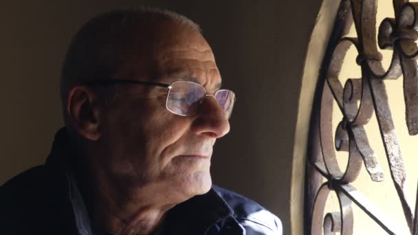 Старый грустный и заботливый человек у окна закрывает глаза — стоковое видео