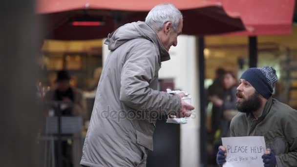 La bondad de la gente El viejo trae el desayuno a un vagabundo en la calle — Vídeo de stock