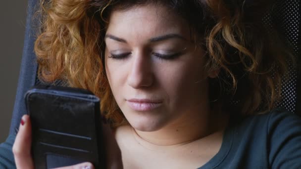 Mooi en relaxte vrouw leest een bericht op haar mobiel en glimlachen — Stockvideo