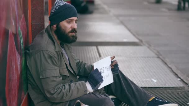 einsame traurige Obdachlose, die auf der Straße sitzen und um Almosen bitten