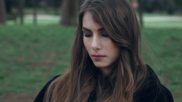 Triste e pensativa menina bonita olha para algo no parque — Vídeo de Stock