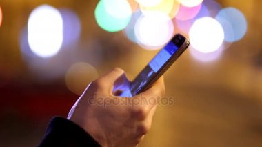 Smartphone, arka planda şehir ışıkları kullanarak adamın elini