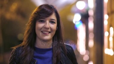Güzel esmer sokakta yürüme ve kameraya, geceleri gülümseyen