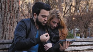tablet ile oynarken parkta bir bankta rahat Çift
