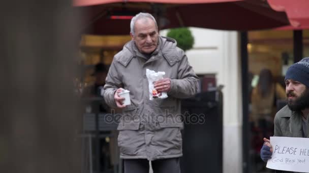 Doux vieillard compatissant apporte le petit déjeuner à un mendiant dans la rue — Video