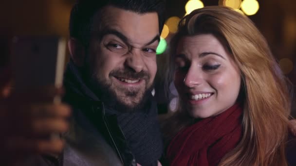 Sonriendo pareja haciendo divertido selfie en la noche en la ciudad, de cerca — Vídeos de Stock
