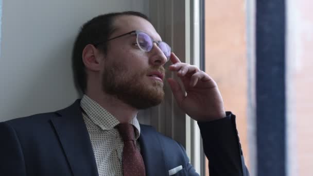 Depressed shocked businessman lays on his eyeglasses looking out of the window — Stock Video