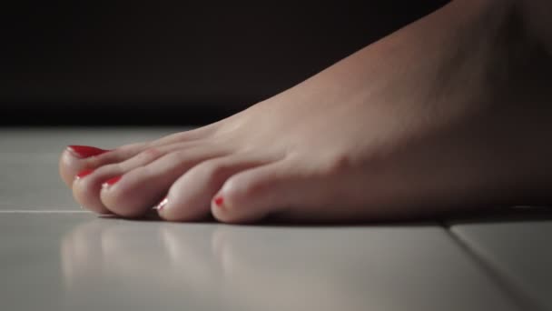 Primer plano en los pies desnudos de la mujer con esmalte de uñas rojas caminando por el suelo — Vídeos de Stock