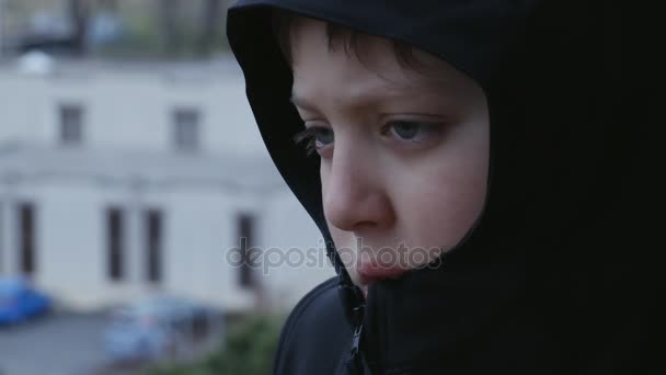 Close up sad and thoughtful child with balck hood, outdoor — стоковое видео