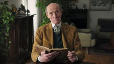 Masada oturan eski ve zarif iş adamı kitap okuma