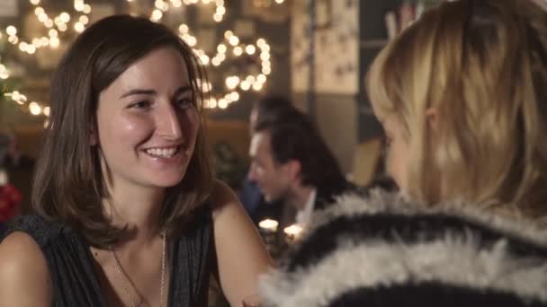 Улыбающаяся счастливая брюнетка болтает с подругой в баре — стоковое видео
