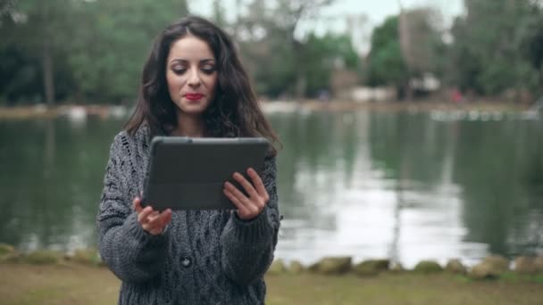 Γελώντας Smiling, όμορφη γυναίκα χρησιμοποιεί το tablet στο πάρκο — Αρχείο Βίντεο