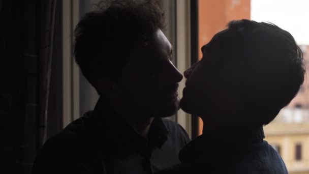 Gay homens silhueta beijos docemente perto o janela — Vídeo de Stock