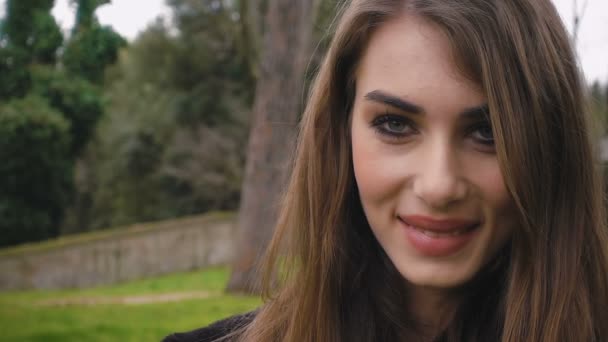Zamknąć na piękną kobietę uśmiechający się w parku - w zwolnionym tempie — Wideo stockowe