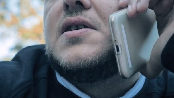 Close-up op iemands mond met baard tijdens het gesprek op de telefoon - buiten — Stockvideo