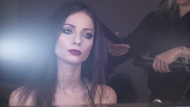 Zamyślony piękny model patrząc w lustro, gdy stylista włosów działa na jej — Wideo stockowe