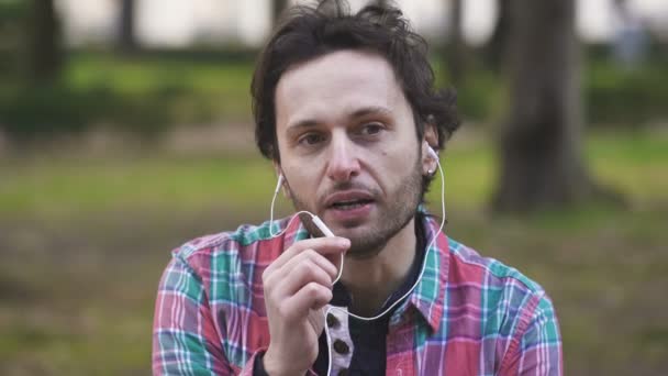 Spokojny człowiek, w parku, rozmawia przez telefon z słuchawki — Wideo stockowe