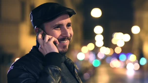 Glimlachende man praten over de telefoon in de stad bij nacht — Stockvideo