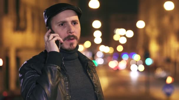 Hombre enojado y nervioso hablando por teléfono, fondo de la ciudad iluminada por la noche — Vídeos de Stock