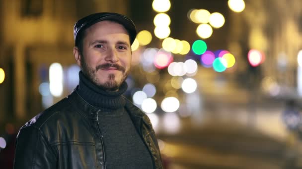 Portret van knappe man die lacht op de camera met in de achtergrond stad licht — Stockvideo