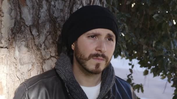 Junger ernsthafter und besorgter Mann lehnt an einem Baum — Stockvideo