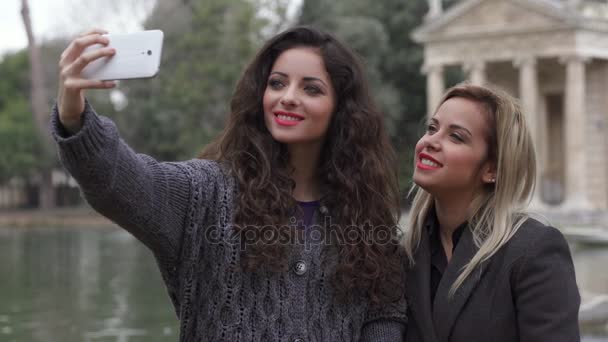 Fazendo Selfie no parque: duas mulheres bonitas fazendo uma selfie — Vídeo de Stock