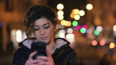 Genç kadın kullanım smartphone gece şehir içinde çok mutlu 