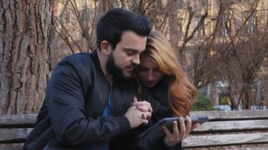 tablet ile parkta genç çift tutkuyla öper