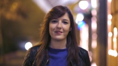 Sokakta yürüyen ve kameraya, geceleri gülümseyen güzel kadın