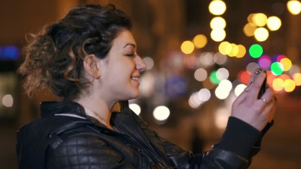 Улыбающаяся красивая женщина снимает смешное селфи, городские ночи на заднем плане — стоковое видео