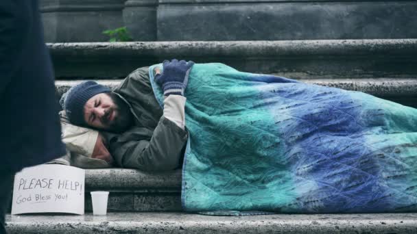 Сонний бездомний на вулиці прокидається, коли чоловік залишає свої милостині — стокове відео