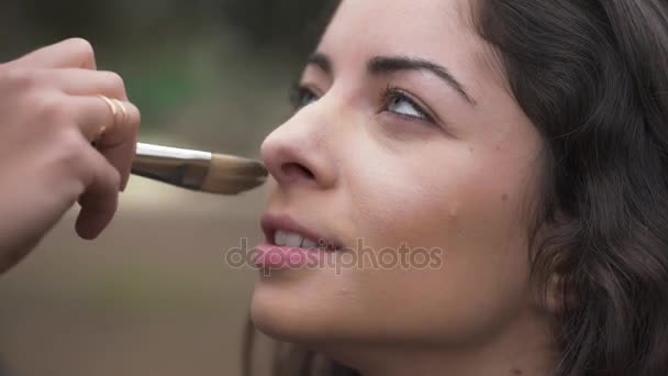 Hermosa modelo charlando con maquillaje artista mientras pone su maquillaje — Vídeo de stock