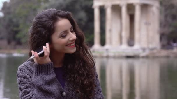 Усміхнений, щаслива мила жінка розмовляє по телефону на відкритому повітрі — стокове відео